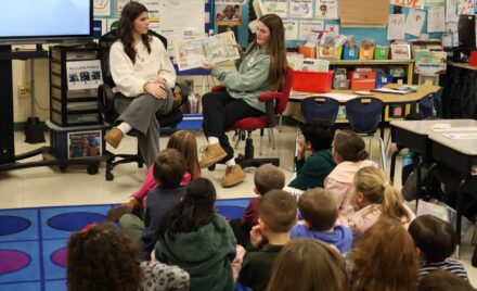 Chelmsford High School National English Honor Society members Ellen Griswold and Maeve Chalmers read to students in Mrs. Bullock's first grade class at South Row Elementary School.