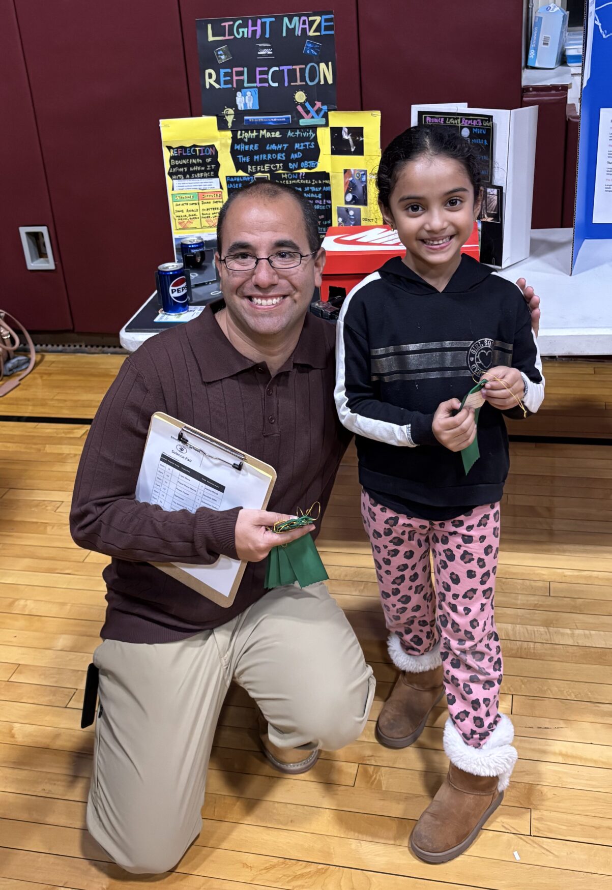 IMG_3165 South Row Elementary School Assistant Principal Dr. Jayson Ramalho poses with first grader Aadira Ramji in front of her science fair project exploring light maze reflection.